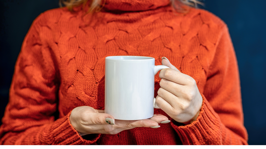 a person in an orange sweater holding a white mug