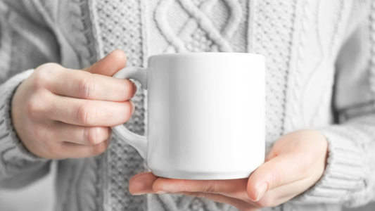 a person is holding a white mug in their hands