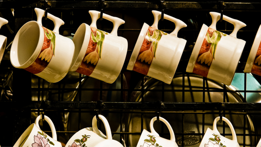 many cups and saucers are hanging on a rack