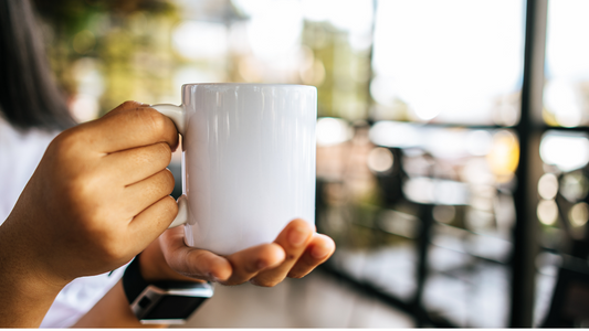 a person holding a coffee mug in front of a window