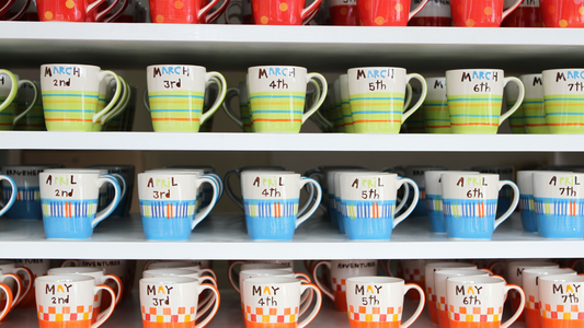 many colorful mugs are on shelves in a store