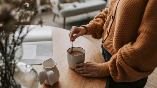 A person in an orange sweater is holding a cup of coffee