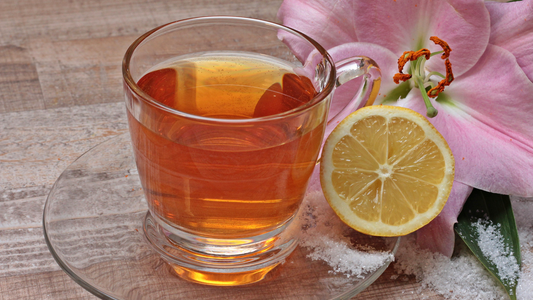 a cup of tea with lemon and flowers on a wooden table