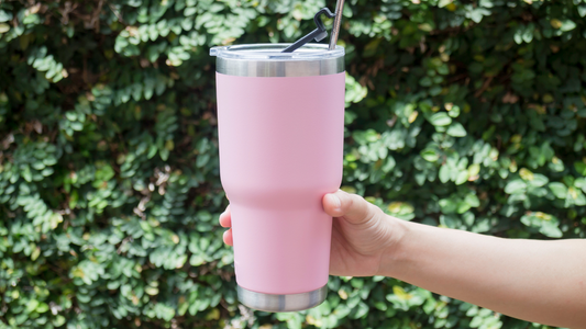 a person holding up a pink tumbler with a straw